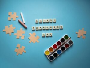 Colorful autism awareness concept with puzzle and watercolor set on a blue background.