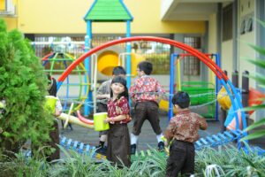 Group of children in traditional clothing playing at a vibrant outdoor playground.