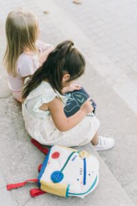 Two young girls drawing on chalkboards while sitting outdoors, expressing childhood creativity.